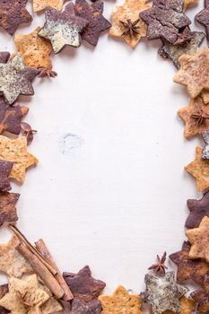 Assorted christmas ginger cookies with cinnamon sticks, pinecones over white wooden table. Christmas cooking background. Six pointed star cookies