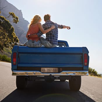 Shot of a young man pointing toward something while on a road trip with his girlfriend.