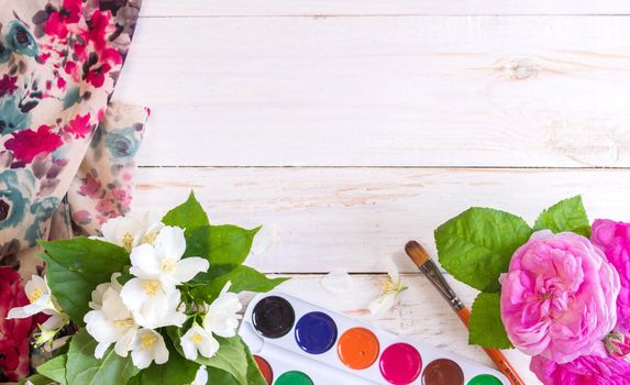 Desk of creative worker. Paints, brush and flowers. Top view background