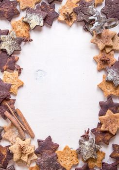 Assorted christmas ginger cookies with cinnamon sticks, pinecones over white wooden table. Christmas cooking background. Six pointed star cookies