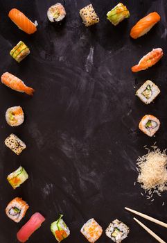 Overhead shot of sushi on dark background. Sushi rolls, nigiri, rice, soy sauce, сhopsticks. Asian food background. Space for text. Sushi set....