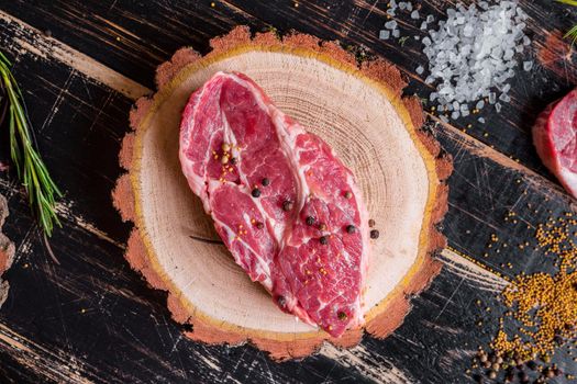 Raw meat steak on dark wooden background ready to roasting