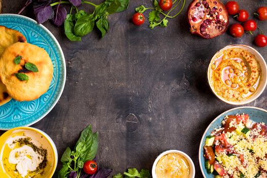 Table served with middle eastern traditional vegetarian dishes. Hummus, tahini, pitta, couscous salad and buttermilk dip with olive oil. Dinner party