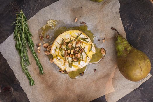 Delicious beautiful baked camembert with honey, walnuts, herbs and pears