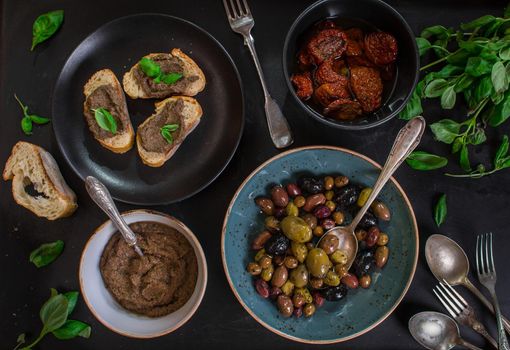 Table served with bread, tapenade, assorted olives, dried tomatoes in olive oil and basil. Dinner table with french provence appetizers and canapes