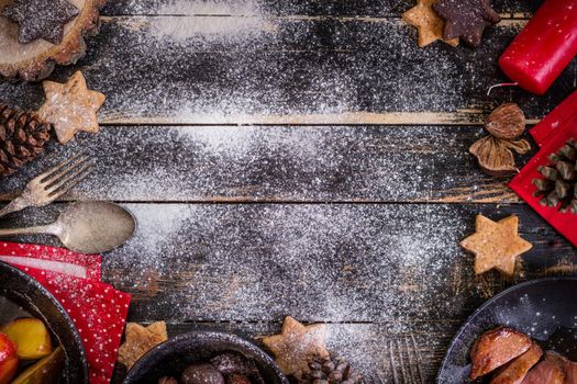 Christmas dinner table served with roasted duck breast, baked apples, chestnuts, gingerbread cookies. Decorated with red candles, pine cones, snow. Christmas background with free space for text. Xmas concept