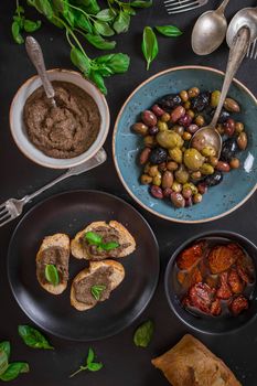 Table served with bread, tapenade, assorted olives, dried tomatoes in olive oil and basil. Dinner table with french provence appetizers and canapes