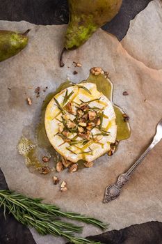 Delicious beautiful baked camembert with honey, walnuts, herbs and pears