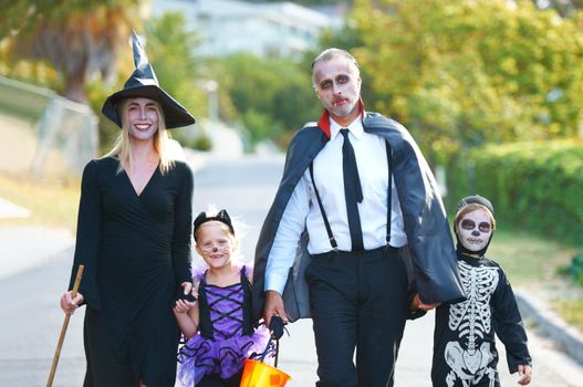 A cute family dressed up for Halloween walking down their street.