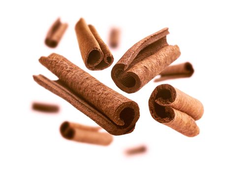 Cinnamon sticks levitate on a white background.