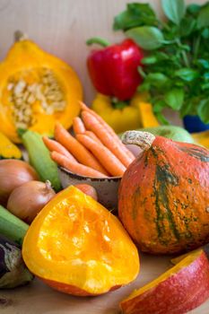 Fresh sliced pumpkin and assorted vegetables. Autumn photo. Healthy eating. Sliced pumpkin, zucchini, squash, bell peppers, carrots, onions, cut garlic, tomatoes, eggplant, corn cob, rucola and basil. Selective focus