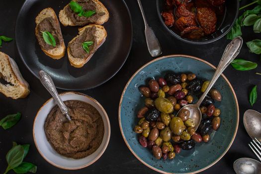 Table served with bread, tapenade, assorted olives, dried tomatoes in olive oil and basil. Dinner table with french provence appetizers and canapes