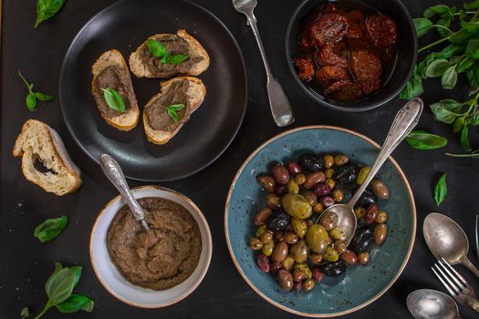 Table served with bread, tapenade, assorted olives, dried tomatoes in olive oil and basil. Dinner table with french provence appetizers and canapes