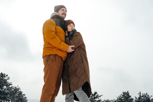Young couple in love outdoor in snowy winter forest having a walk