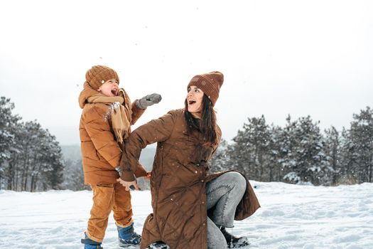 Woman with a little son on a winter hike in the snowy forest together