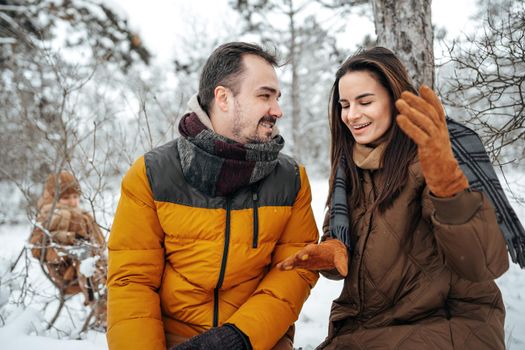 Young couple in love outdoor in snowy winter forest having a walk