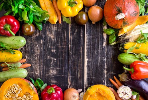 Fresh vegetables on a old rustic dark textured table. Autumn background. Healthy eating frame. Sliced pumpkin, zucchini, squash, bell peppers, carrots, onions, cut garlic, tomatoes, eggplant, corn cob, rucola and basil. Top view. Space for text