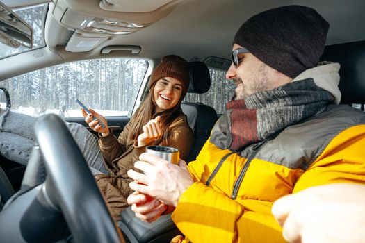 Family couple sitting in car in winter clothes iin snow forest, close up