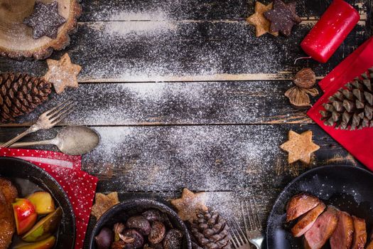 Christmas dinner table served with roasted duck breast, baked apples, chestnuts, gingerbread cookies. Decorated with red candles, pine cones. Christmas background with free space for text. Xmas concept