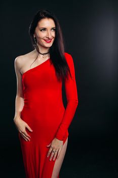 Studio portrait of sexy and beautiful girl in glamour red dress posing at gray studio. Gorgeous brunette woman before dancing party. Female after beauty salon. Copy space.