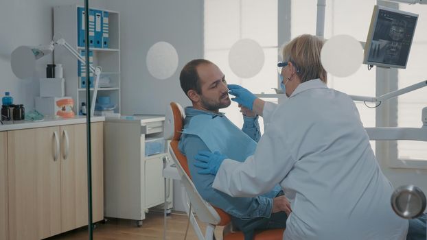 Patient with toothache explaining pain to dentist at oral care clinic, receiving consultation and orthodontic treatment. Dentistry expert examining denture problem before procedure.
