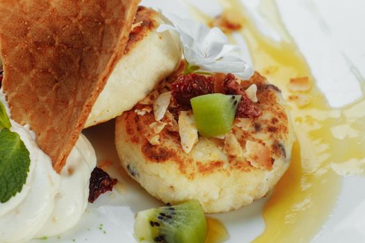 An ideal breakfast. Cottage cheese pancakes with caramel, almonds and cream sauce in a white plate. Ukrainian syrniki.