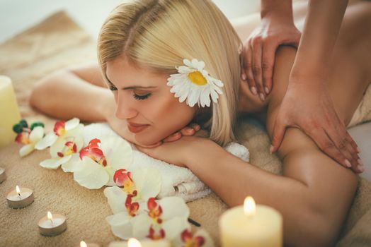 Beautiful woman enjoying during a shoulder massage at a spa. 