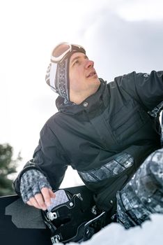 Beautiful young smiling man with snowboard enjoying a winter day. 