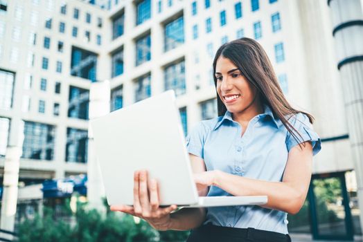 Emotional portrait of a happy and beautiful young businesswoman who working on laptop on the background of a business center.