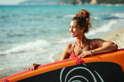Portrait of a beautiful young female surfer is standing on the beach.