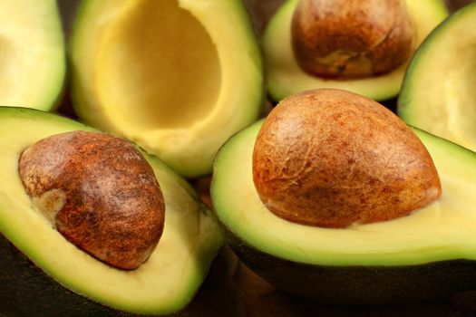 Closeup detail - heap  of avocados cut in half, with brown seeds.