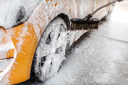 Foam spraying to yellow car wheel, when washed in carwash.