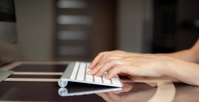 Female hands typing text on the keyboard while exchanging messages with friends via social networks using a computer laptop. A female office worker checks her email while sitting at a desk.