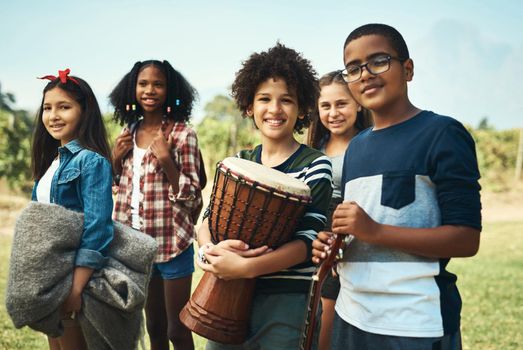 Shot of a group of teenagers playing musical instruments in nature at summer camp.