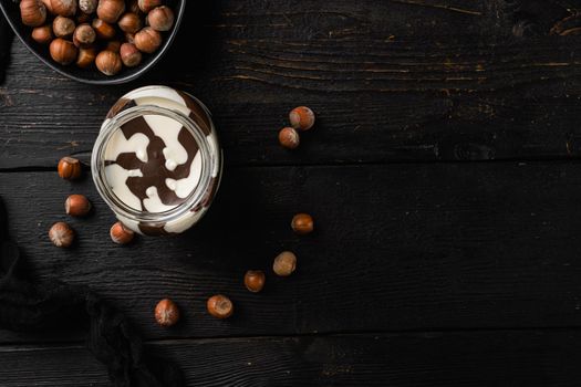 Hazelnut spread with nuts set, on black wooden table background, top view flat lay, with copy space for text