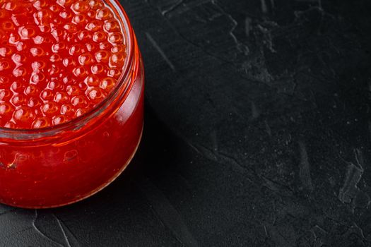 Red salmon caviar jar, on black background with copy space for text