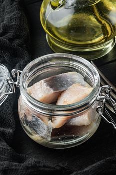 Sliced herring in oil marinated, on black wooden table background