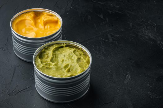 Canned guacamole and cheese dip in can, on black background with copy space for text