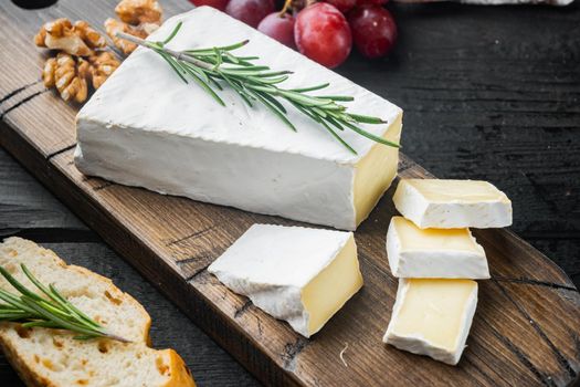 Slice of brie farmhouse creamy soft cheese set, on black wooden table