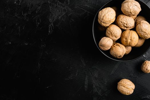 Walnuts with shells set, on black dark stone table background, top view flat lay, with copy space for text