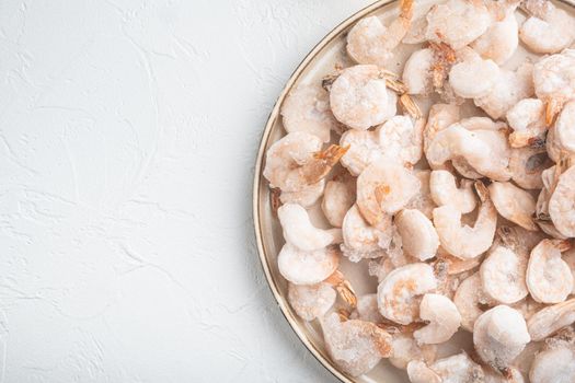 Boiled and frozen shrimps set, on plate, on white background, top view flat lay, with copy space for text