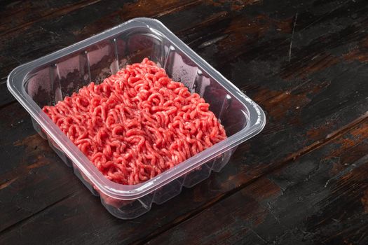 Raw Minced Meat in a transparent Plastic Container set, on old dark wooden table background, with copy space for text