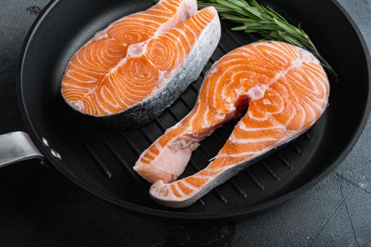 Raw salmon steak on grill skillet, over grey background.