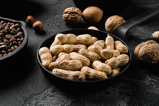 Dried peanuts. Tasty groundnuts set, on black dark stone table background