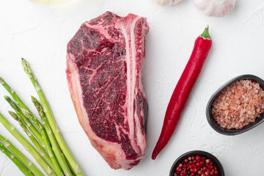 Dry aged Club Steak, seasoning set, on white stone background