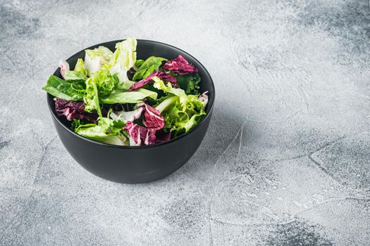 Bowls with mixed shredded salad lettuce fresh leaves, on gray background
