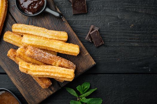 Churros with caramel, Traditional Spanish cusine, on black wooden table background, top view flat lay with space for text, copyspace