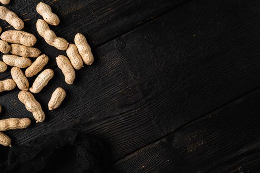 Organic peanuts in shell set, on black wooden table background, top view flat lay, with copy space for text
