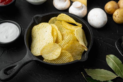 Home made potato chips set, on black stone background