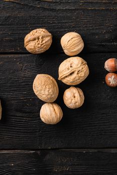 Whole organic walnuts, on black wooden table background, top view flat lay, with copy space for text